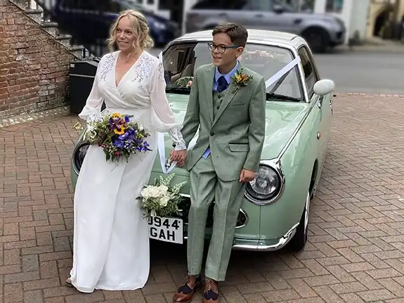 Bride arriving in a chauffeur-driven Nissan Figaro convertible wedding car